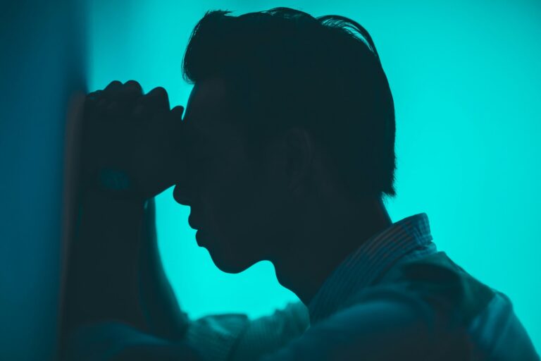 Silhouetted man leaning against wall in distress, symbolizing cannabis-induced anxiety